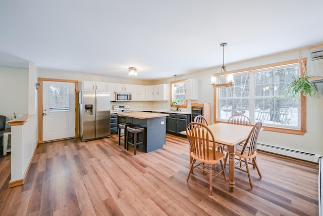 dining room featuring a baseboard radiator, light wood-style flooring, and a chandelier