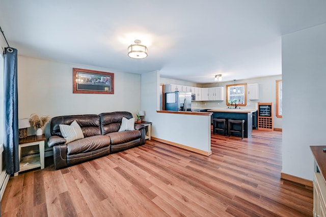 living room with light wood-style flooring, baseboards, and baseboard heating