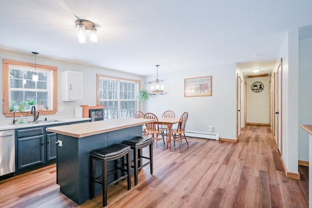 kitchen featuring a breakfast bar, light wood-style flooring, stainless steel dishwasher, and a sink