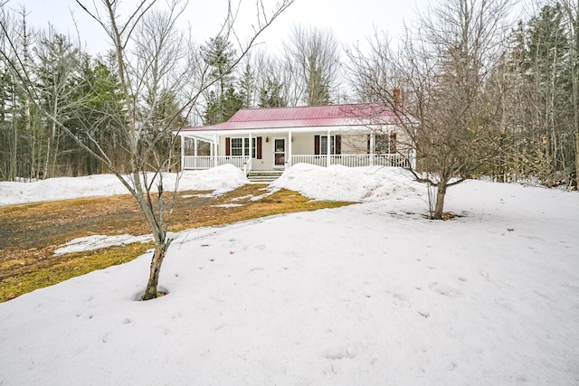 view of front of property featuring a chimney, a porch, and metal roof