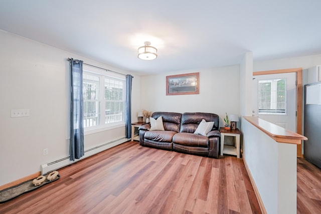 living room featuring light wood finished floors, a healthy amount of sunlight, and baseboard heating