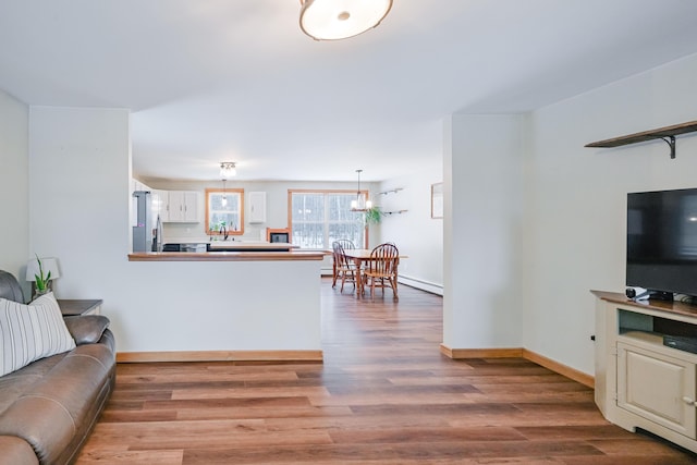 living room with baseboard heating, baseboards, and wood finished floors