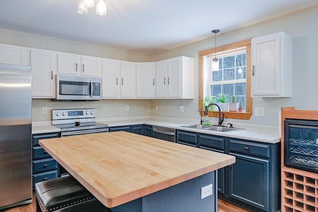 kitchen with butcher block countertops, white cabinets, stainless steel appliances, and a sink