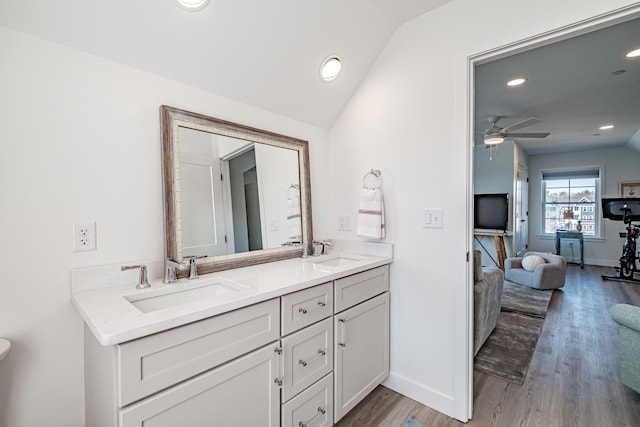 bathroom featuring a sink, wood finished floors, and vaulted ceiling