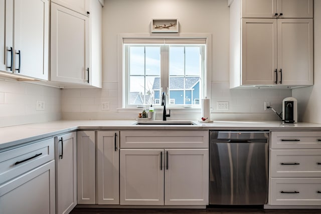 kitchen with tasteful backsplash, a sink, light stone countertops, white cabinets, and stainless steel dishwasher