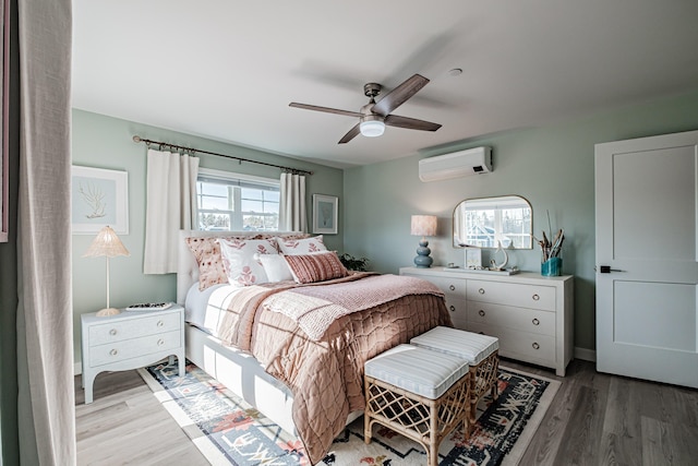 bedroom with an AC wall unit, light wood-style floors, and ceiling fan