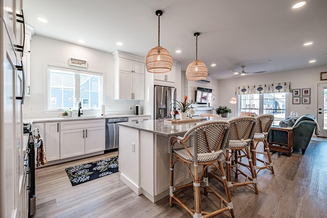 kitchen with a wealth of natural light, appliances with stainless steel finishes, a center island, and a sink