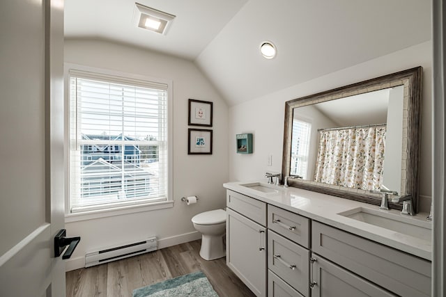 bathroom with a sink, a baseboard radiator, wood finished floors, and vaulted ceiling