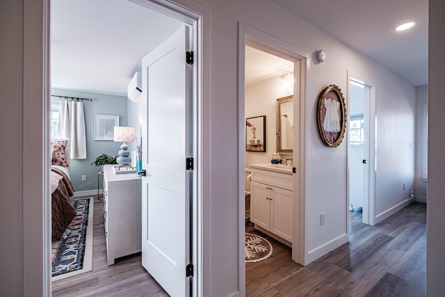 hall with recessed lighting, baseboards, light wood finished floors, and a wall mounted AC