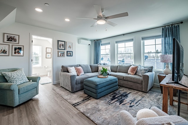 living room featuring a baseboard heating unit, an AC wall unit, plenty of natural light, and wood finished floors