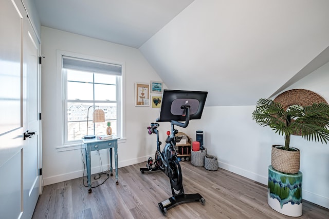 exercise area with baseboards, wood finished floors, and vaulted ceiling