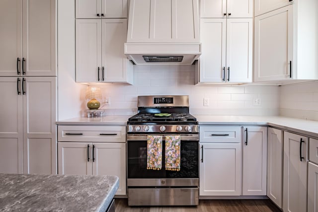 kitchen featuring stainless steel gas range oven, tasteful backsplash, wood finished floors, and custom range hood