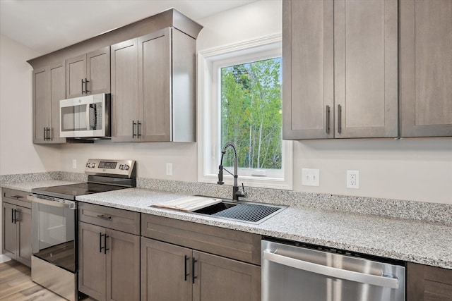 67 Stacey Ln, Kenduskeag, ME 04450 - kitchen featuring appliances with stainless steel finishes, a sink, light wood-style floors, and light stone counters