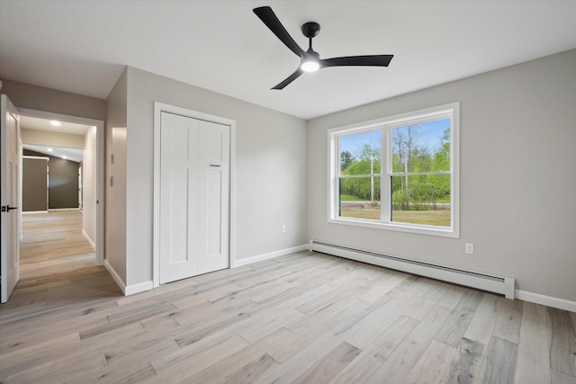 67 Stacey Ln, Kenduskeag, ME 04450 - unfurnished bedroom with a baseboard radiator, light wood finished floors, baseboards, a closet, and a ceiling fan