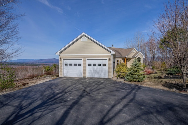 view of front facade featuring a garage, a mountain view, and aphalt driveway