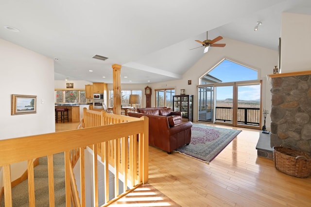 living area featuring visible vents, ceiling fan, high vaulted ceiling, ornate columns, and light wood-style flooring