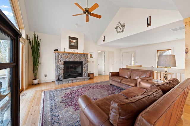 living room with a ceiling fan, high vaulted ceiling, plenty of natural light, and a stone fireplace