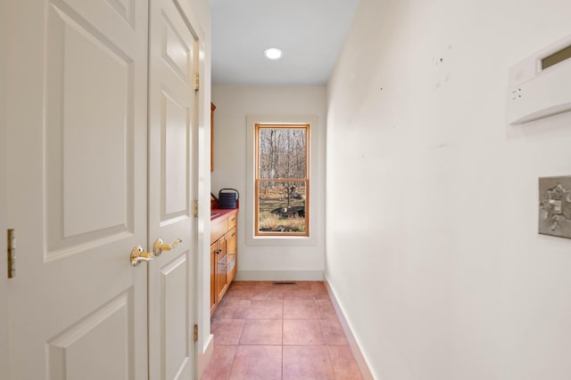 corridor with baseboards and light tile patterned floors
