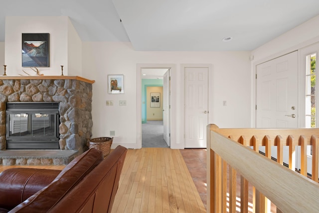 living room featuring baseboards, light wood-style flooring, and a fireplace