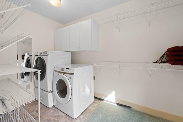 clothes washing area featuring washer and clothes dryer and cabinet space