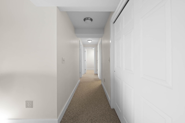 hallway with baseboards and light carpet