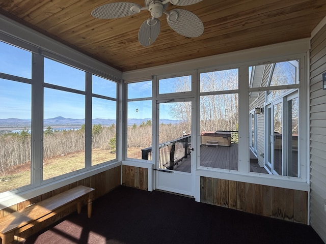 unfurnished sunroom featuring ceiling fan and a mountain view