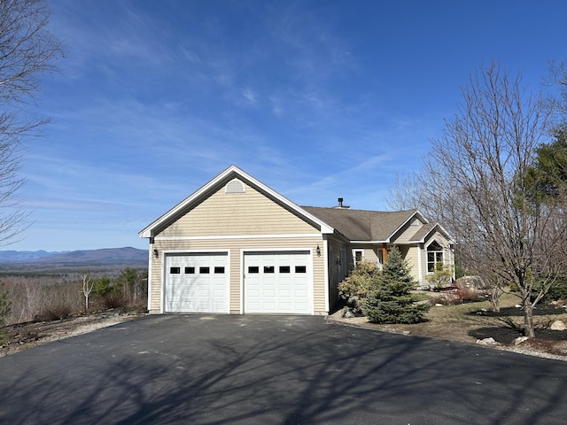 ranch-style house with a garage, a mountain view, and aphalt driveway