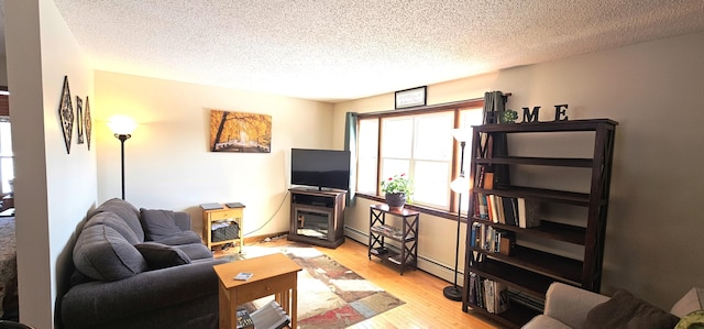 living area featuring a baseboard radiator, light wood-style floors, and a textured ceiling