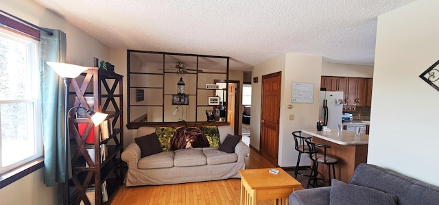 living area featuring light wood finished floors, a textured ceiling, and ceiling fan