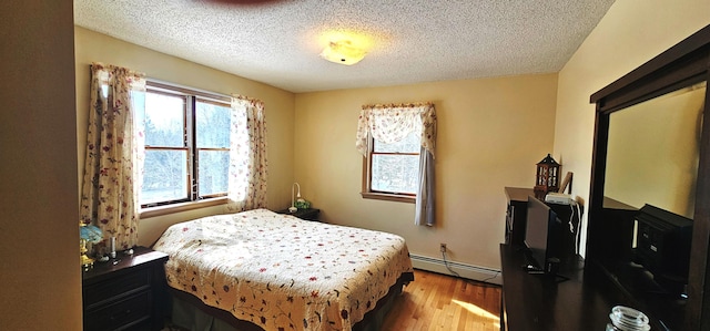 bedroom with light wood-style flooring, a textured ceiling, and baseboard heating