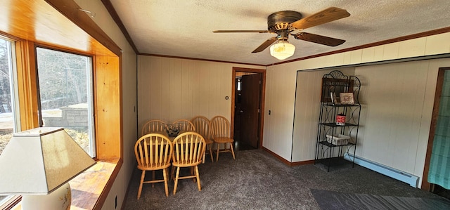 dining room with a baseboard heating unit, a textured ceiling, carpet, a ceiling fan, and ornamental molding