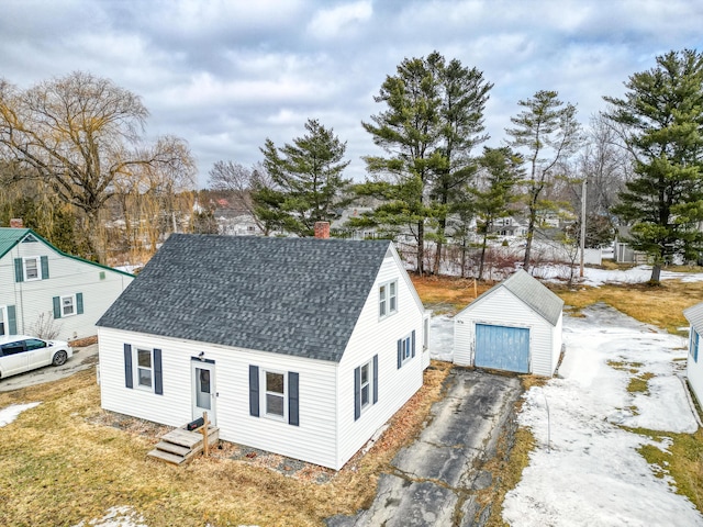 cape cod home with an outbuilding, roof with shingles, a chimney, a garage, and aphalt driveway