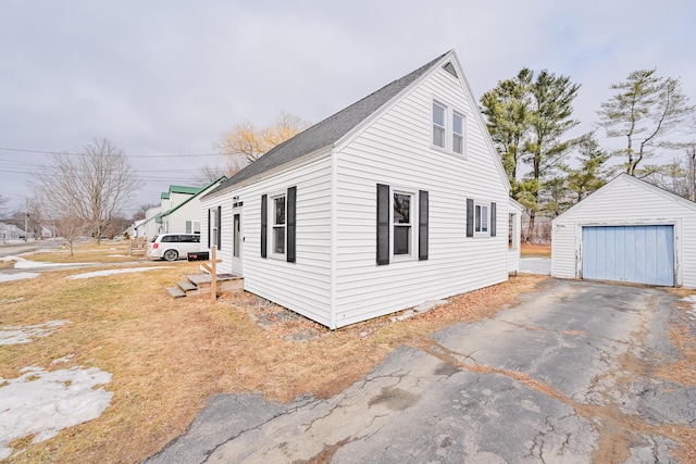 view of property exterior with an outbuilding, a garage, roof with shingles, and aphalt driveway