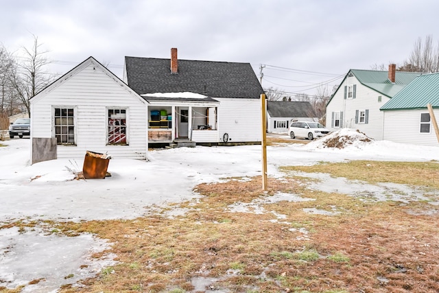 snow covered rear of property with a chimney