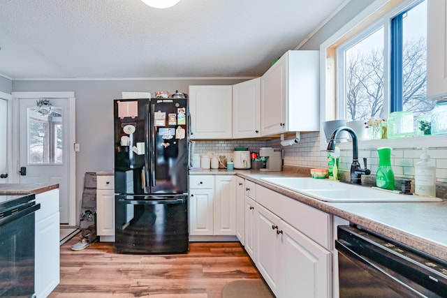 kitchen with light wood-type flooring, black appliances, a sink, white cabinetry, and decorative backsplash