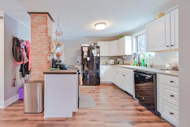 kitchen with light wood finished floors, a sink, decorative backsplash, black appliances, and crown molding