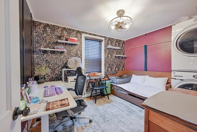 office space featuring stacked washer and clothes dryer, wallpapered walls, and an inviting chandelier