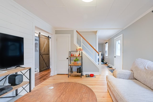 living room with wood finished floors, baseboards, stairs, crown molding, and a barn door