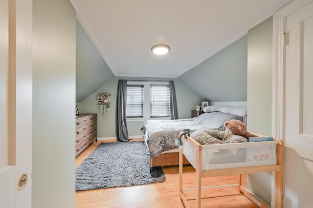 bedroom with baseboards, lofted ceiling, and wood finished floors