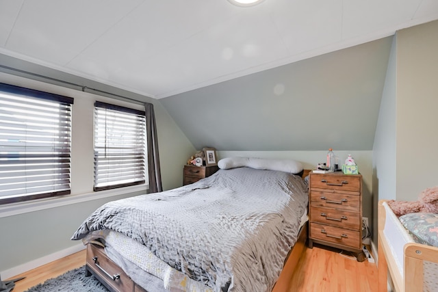 bedroom with vaulted ceiling, baseboards, and light wood-type flooring