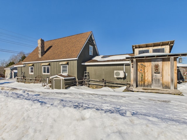 snow covered rear of property featuring a chimney