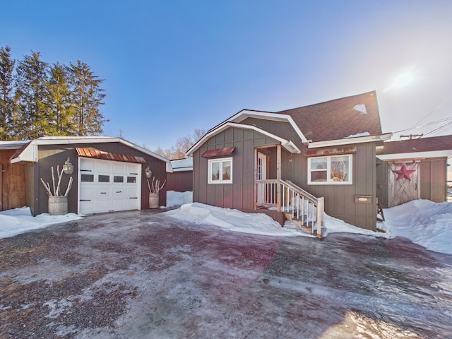 view of front facade featuring driveway, board and batten siding, an outdoor structure, a shingled roof, and a garage