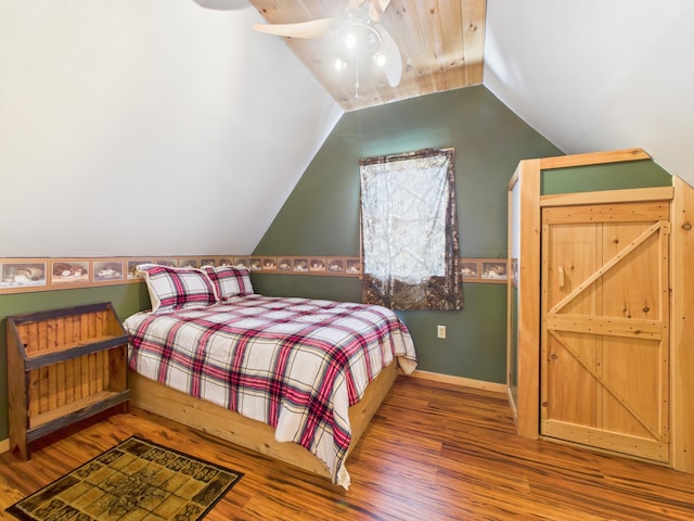 bedroom featuring lofted ceiling, wood finished floors, baseboards, and ceiling fan