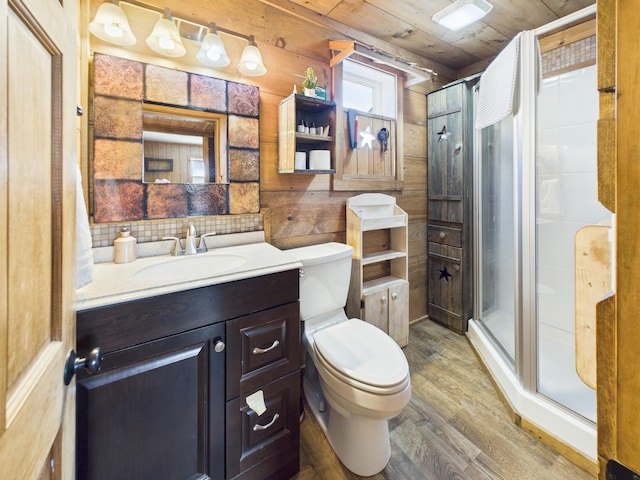 bathroom with wooden walls, toilet, a stall shower, wood finished floors, and vanity