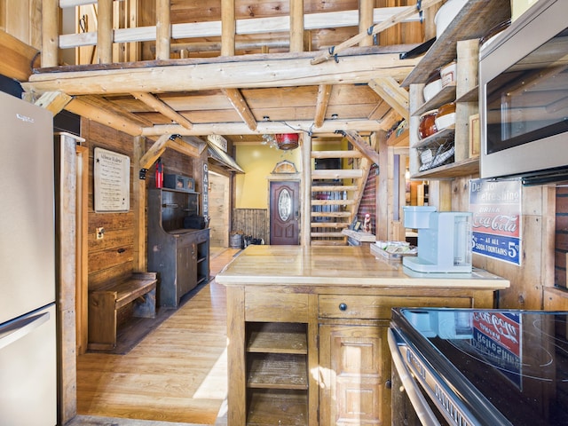 kitchen with open shelves, light wood-type flooring, wooden walls, and freestanding refrigerator