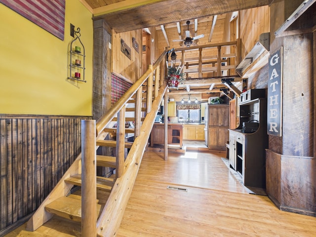 stairs with visible vents, ceiling fan, wooden ceiling, wood finished floors, and high vaulted ceiling