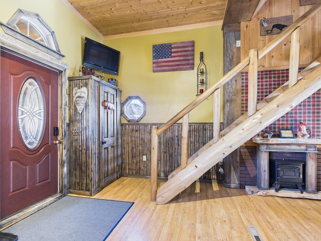 entrance foyer with stairs, wooden ceiling, wood finished floors, and ornamental molding