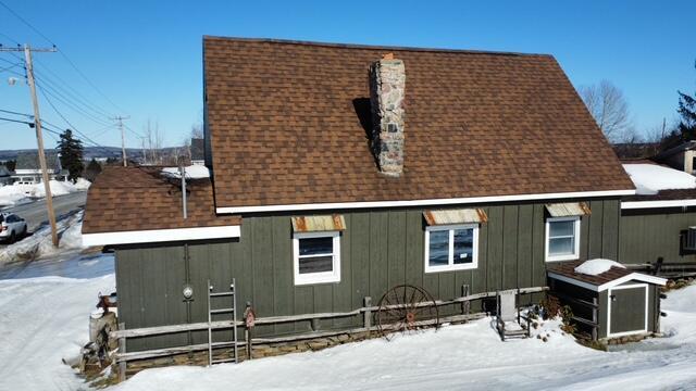 exterior space with roof with shingles and a chimney