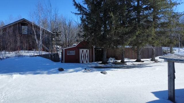 yard layered in snow featuring an outbuilding and fence