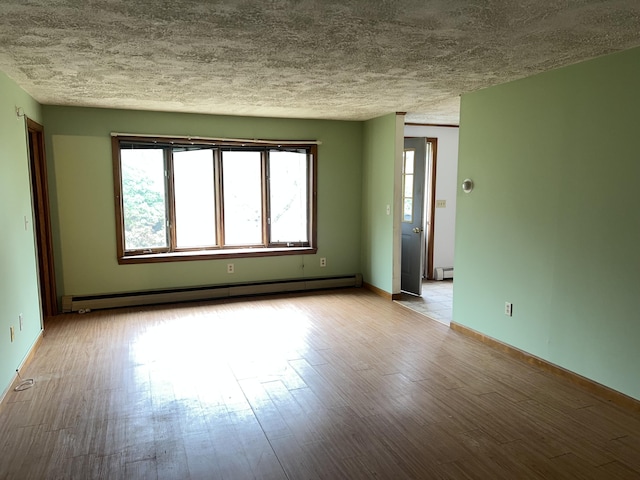 unfurnished room featuring a textured ceiling, wood finished floors, baseboard heating, and a baseboard heating unit